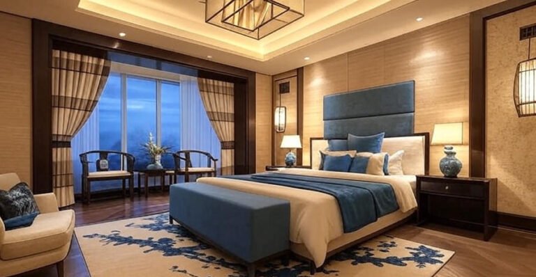 Luxurious hotel bedroom featuring a blue-and-white palette, a large bed with a blue headboard, dark wood accents, and a window view at dusk.